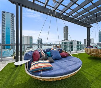 a large swing on a roof terrace with a view of the city